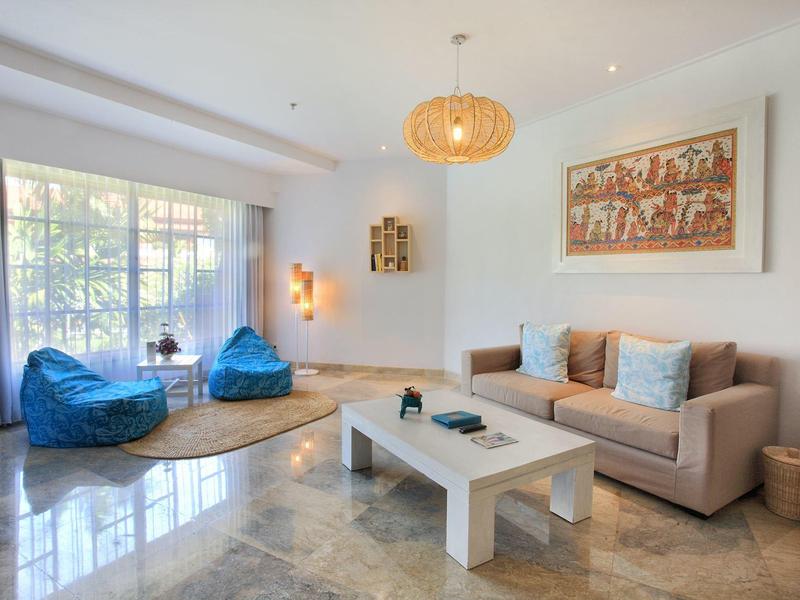 Soggiorno luminoso con divani, poltrone colorate e tavolino in un'atmosfera accogliente.