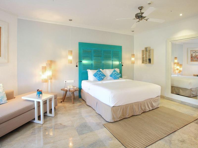 Camera d'hotel elegante con letto matrimoniale, divano, tappeto e decorazioni moderne.