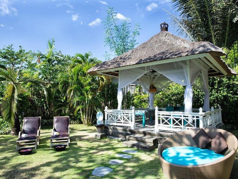 Gazebo esotico con sdraio e jacuzzi in un giardino tropicale luminoso.