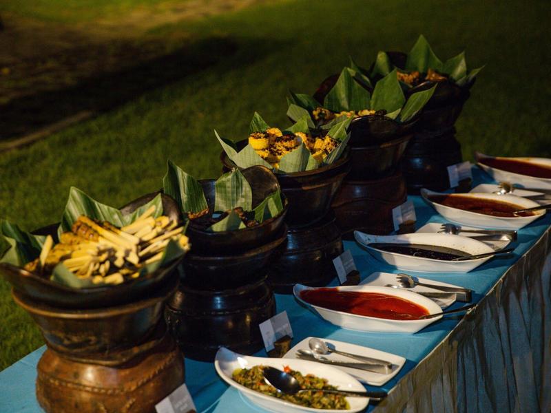 Buffet all'aperto con salse e accompagnamenti in ciotole e piatti bianchi.