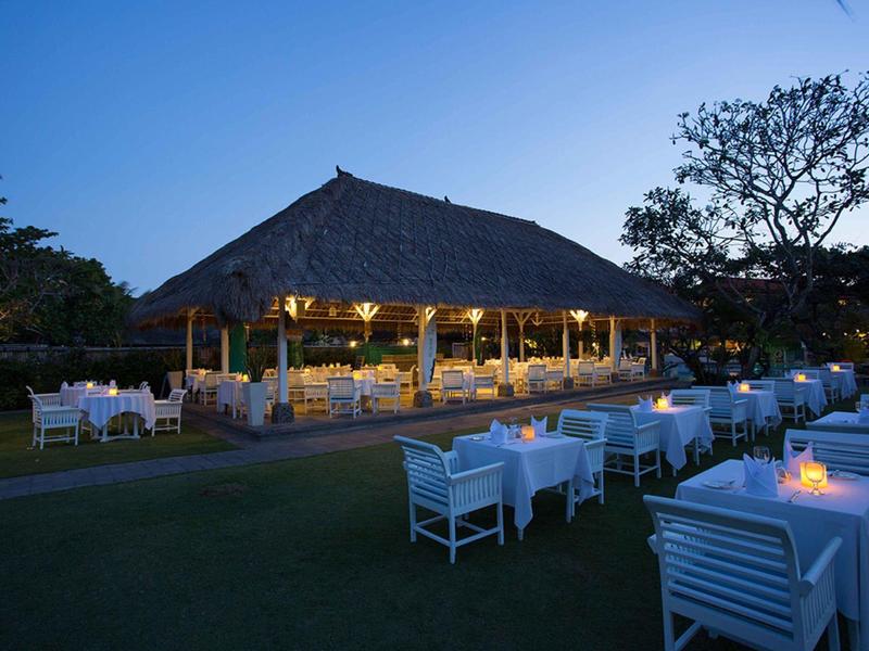 Ristorante all'aperto elegante con tavoli bianchi e atmosfera al crepuscolo.