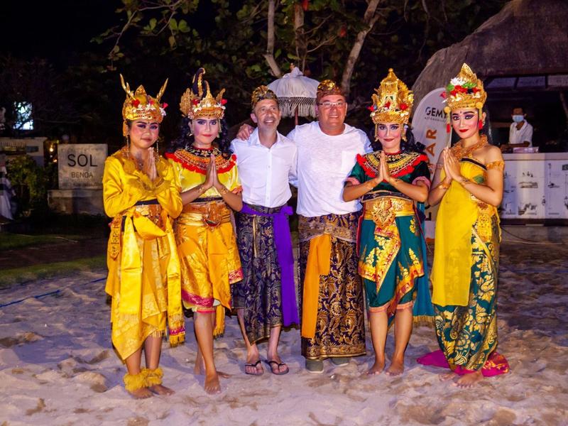 Quattro donne in abiti tradizionali gialli con due uomini in abbigliamento casual.