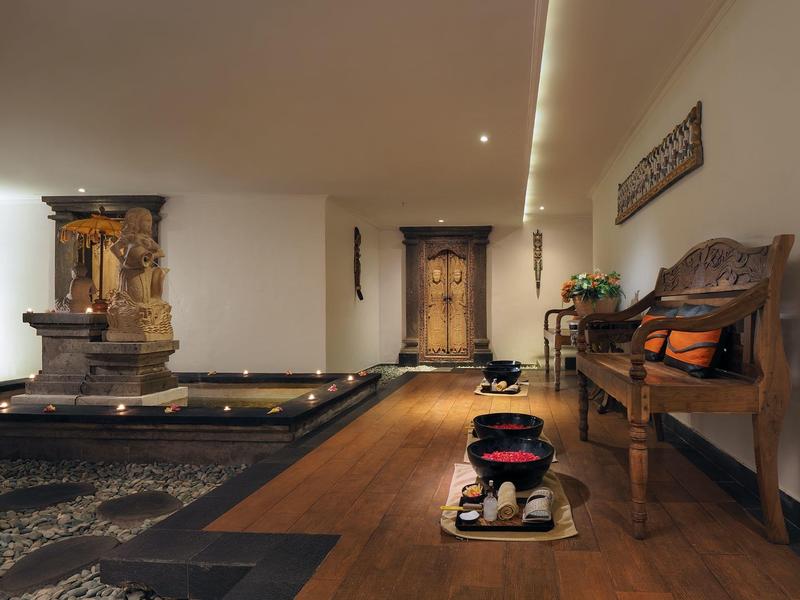 Ingresso hotel elegante con fontana, panche in legno e decorazioni accoglienti.