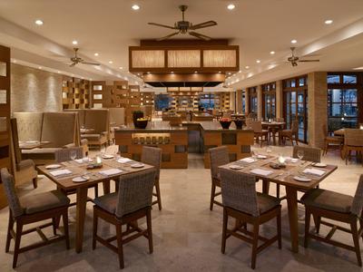 Restaurant élégant avec tables dressées et éclairage chaleureux dans un hôtel.