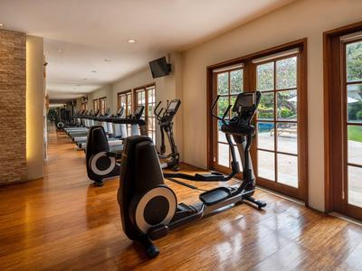 Fitnessraum mit Fokus auf Cardiogeräte und großem Fenster mit Blick nach draußen.