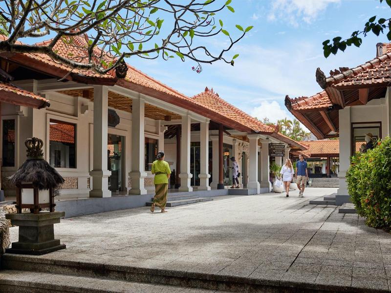 Cour d'hôtel avec architecture traditionnelle et personnes marchant par temps ensoleillé