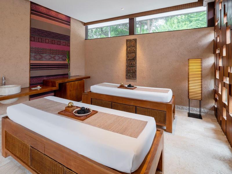 Salle de massage moderne avec deux tables, accents en bois et lumière naturelle.