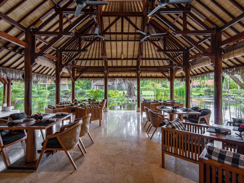 Restaurant ouvert avec toit en bois et décoration moderne donnant sur le jardin.