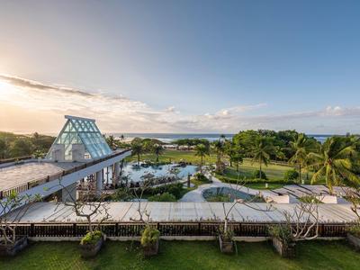 Widok na nowoczesny basen z szklaną konstrukcją i morzem w tle.