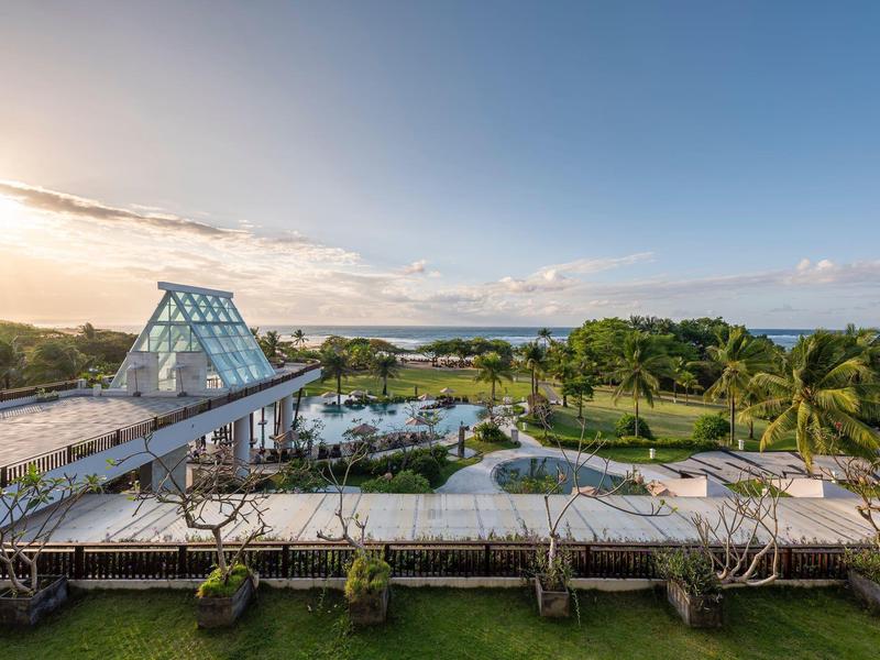 Widok na nowoczesny basen z szklaną konstrukcją i morzem w tle.