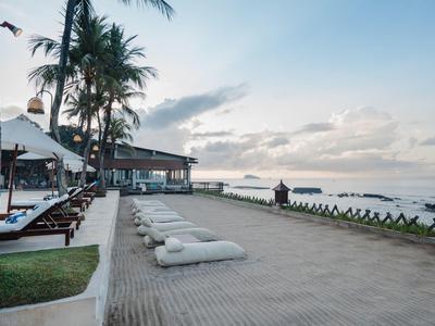 Resort de lujo junto al mar con tumbonas, palmeras y ambiente relajado al atardecer.