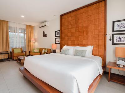 Habitación de hotel moderna con cama grande y zona de estar junto a la ventana.