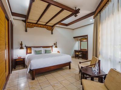 Habitación de hotel acogedora con cama doble, sillas y ventana grande con cortinas.