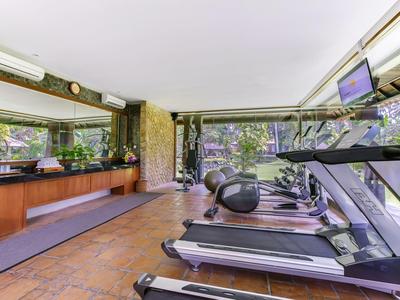 Modern gym with treadmills, elliptical trainer, and large windows overlooking trees.
