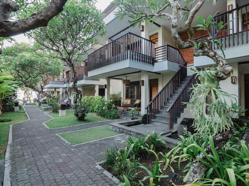 Hotel con senderos exteriores, jardín bien cuidado y balcones en entorno tropical