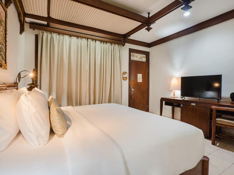 Habitación de hotel acogedora con cama grande, vigas de madera en el techo y televisor sobre un escritorio.