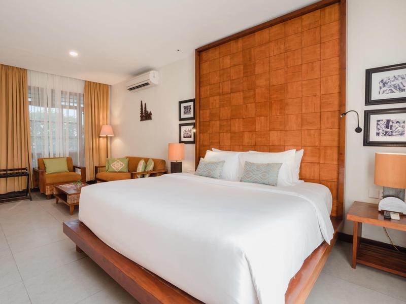 Habitación de hotel moderna con cama grande y zona de estar junto a la ventana.