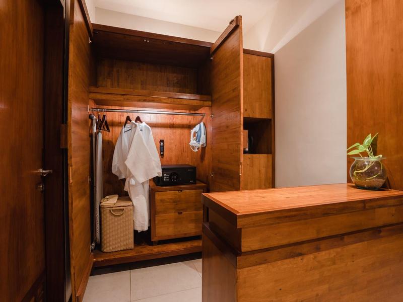 Armario de madera abierto con albornoces y cajones en una habitación luminosa.