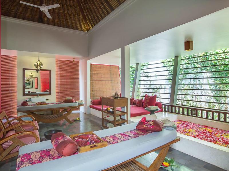 Sala de descanso de spa acogedora con tumbonas y ventana con vista al jardín.