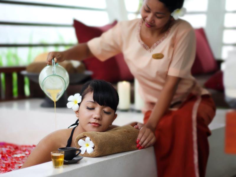 Mujer recibe masaje relajante y le vierten aceite en el spa.