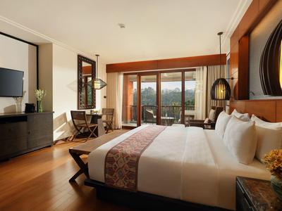 Gemütliches Hotelzimmer mit großem Bett, Holzboden und Balkon mit Blick auf die Berge.