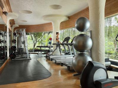 Modern fitnesscentrum met loopbanden, fitnessapparatuur en grote ramen.