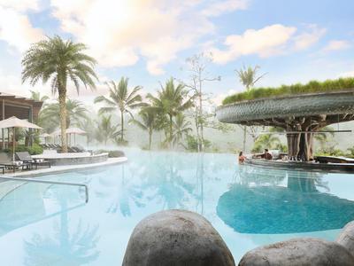 Groot zwembad met palmbomen en mist in een tropisch hotel.