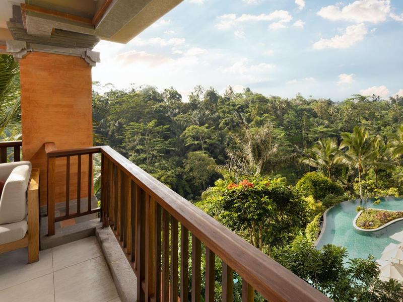 Balkon mit Stuhl und Geländer, Blick auf grünen Dschungel und blauen Pool bei sonnigem Himmel.