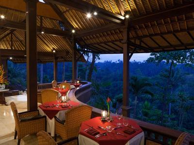 Pohodlná venkovní restaurace s prostřenými stoly a výhledem na tropický les za soumraku.