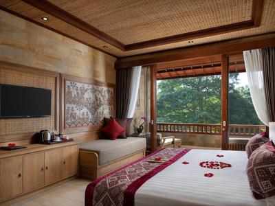 Příjemný hotelový pokoj s velkou postelí, televizí a výhledem na zelenou přírodu z balkonu.