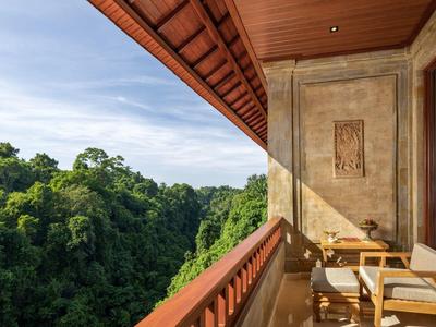 Balkon s židlemi a stolem s výhledem na hustý zelený les a modrou oblohu.