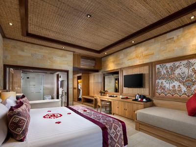 Luxusní hotelový pokoj s velkou postelí, pohovkou, dřevěným stropem a moderním zábavním systémem.