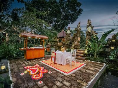 Romantisches, im Freien gelegenes Dinner-Setup mit Tisch, Stühlen und dekorativen Lichtern.