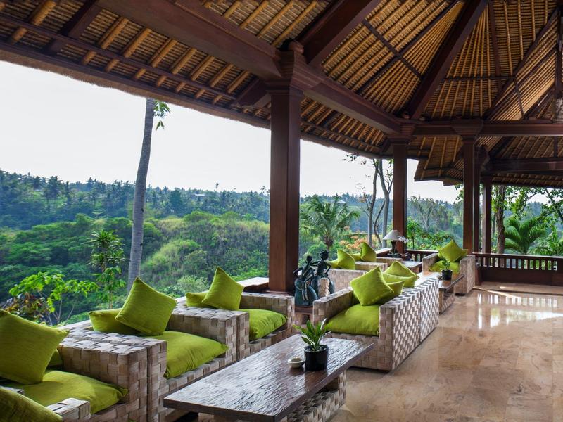 Otevřená odpočinková zóna se zelenými polštáři s výhledem na zalesněné kopce.