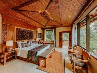 Gezellige hotelkamer met houten meubels, groot bed en uitzicht op groene natuur door ramen.