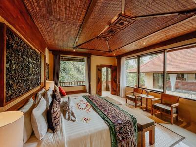 Gezellige hotelkamer met tweepersoonsbed, houten meubels en grote ramen met uitzicht.