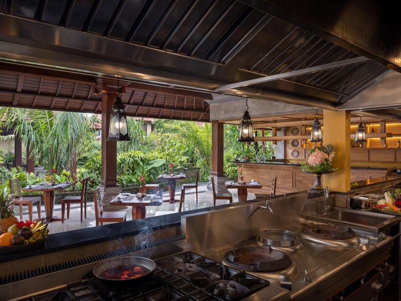 Moderne open hotelkeuken met uitzicht op tropische tuin en eetgedeelte.