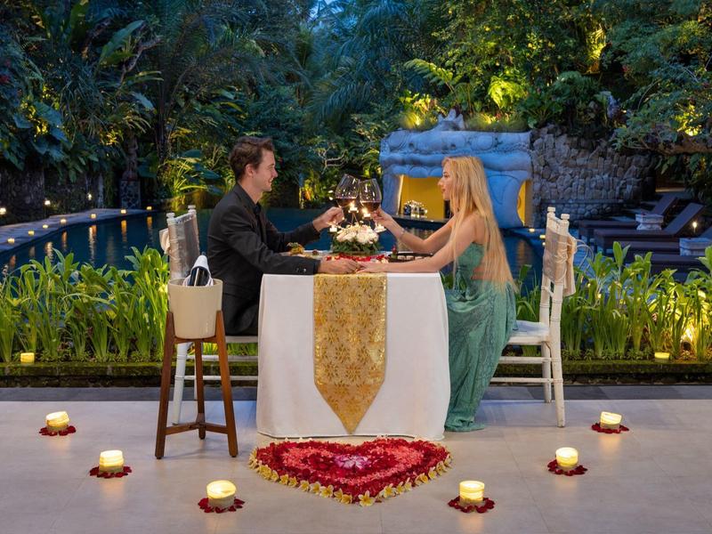 Romantisch diner in de buitenlucht met kaarsen en hartdecoratie naast een vijver.