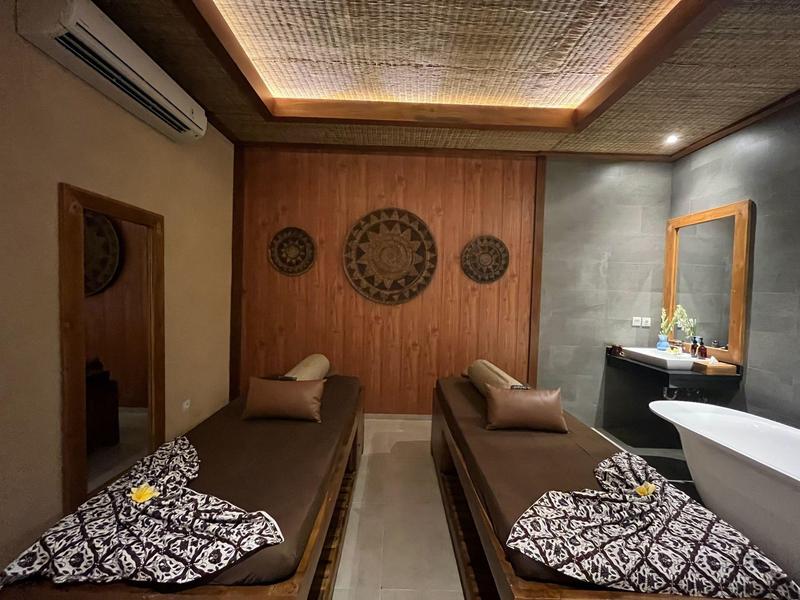 Moderne spa-ruimte met twee massagetafels, decoratieve wandklokken en een vrijstaand bad.