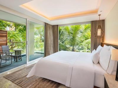 Moderne slaapkamer met groot bed, terraszicht en tropische tuin buiten