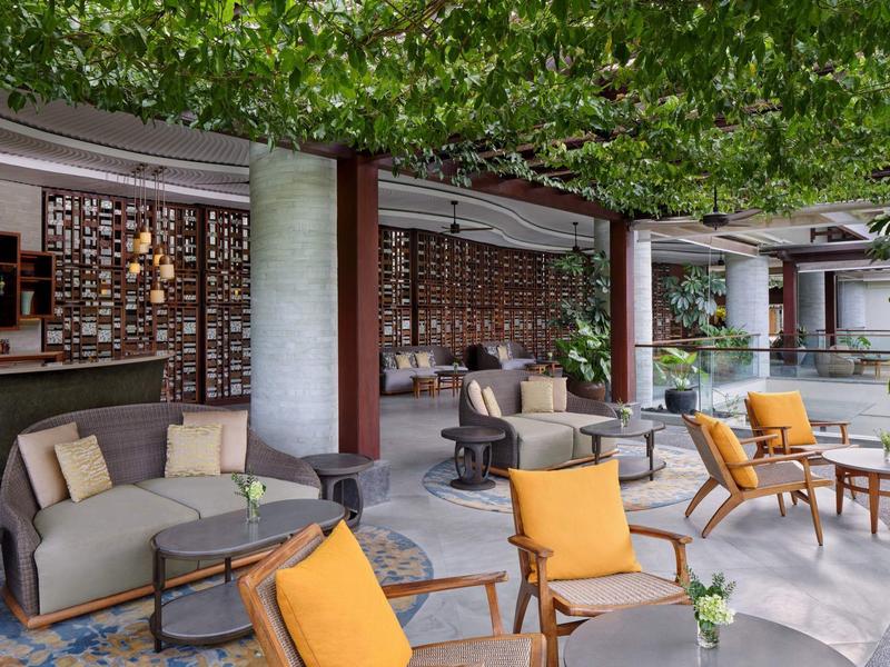 Espace lounge moderne avec chaises et canapés confortables sous un auvent vert.