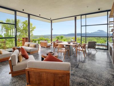 Modern living room with large windows and views of nature and mountains.