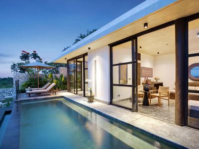Bungalow moderne avec façade en verre, espace de vie ouvert et piscine privée au coucher du soleil.