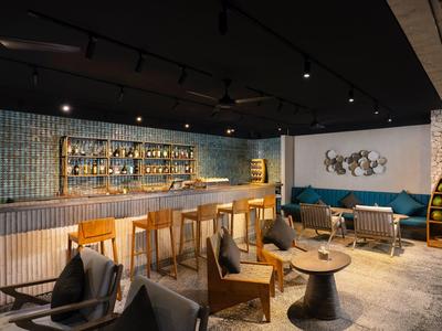 Espace lounge d'hôtel moderne avec accents en bois et bleu, comptoir de bar et sièges confortables.