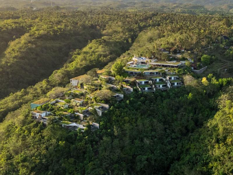 Complexe hôtelier moderne niché sur une colline boisée avec vue sur un paysage verdoyant.