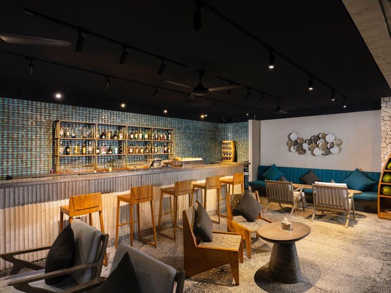 Espace lounge d'hôtel moderne avec accents en bois et bleu, comptoir de bar et sièges confortables.