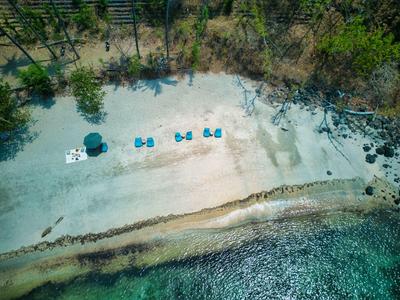 Strand mit weißem Sand, blauem Wasser, Sonnenschirmen und gleichmäßig angeordneten Liegestühlen.