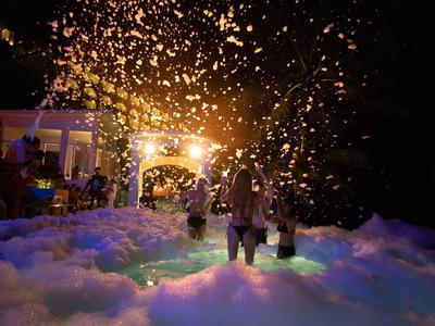 Persone che si rilassano a una festa di schiuma all'aperto illuminata di notte.