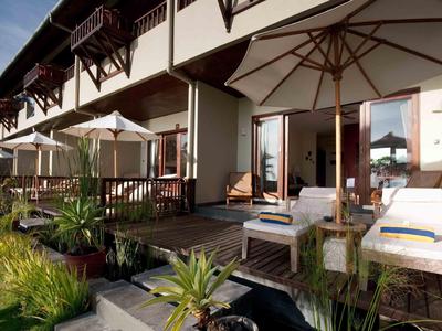 Terras van een hotelkamer met ligstoelen, parasols en tuinmeubilair bij daglicht.