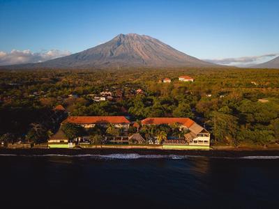 Hotel aan het water met een grote vulkaan op de achtergrond.